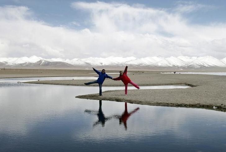 Local tourists poses for a photograph on the shores of Lake Namtso, Tibet Autonomous Region May 10, 2011. Namtso Lake, which means sacred or heaven lake in Tibetan, is 4,718 metres (15,479 feet) above sea level and is the second largest salt-water lake in China next to Qinghai Lake. Picture taken May 10, 2011. REUTERS/Rooney Chen (CHINA - Tags: SOCIETY TRAVEL)