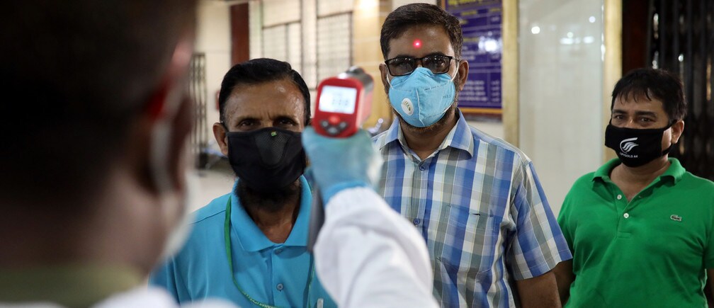 Un personal de seguridad comprueba la temperatura corporal de los clientes en Dhaka, Bangladesh, el 2 de abril de 2020.