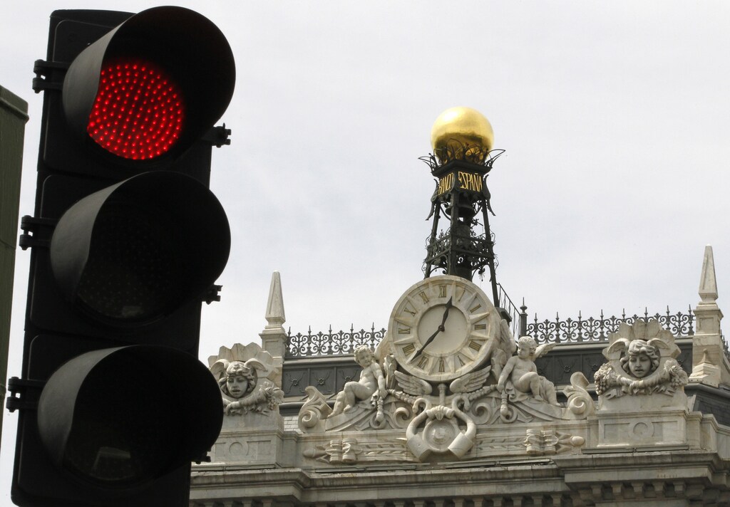 A red traffic light is seen in front of the Bank of Spain headquarters in Madrid June 9, 2012. Spain needs about 40 billion euros in extra capital injected into several banks to allow them to withstand severe economic conditions, the International Monetary Fund said on Friday. The IMF said its "stress test" does not include extra capital that it recommends Spain would need as a buffer to account for restructuring costs and loan losses. REUTERS/Paul Hanna (SPAIN - Tags: BUSINESS POLITICS) - RTR33BZJ