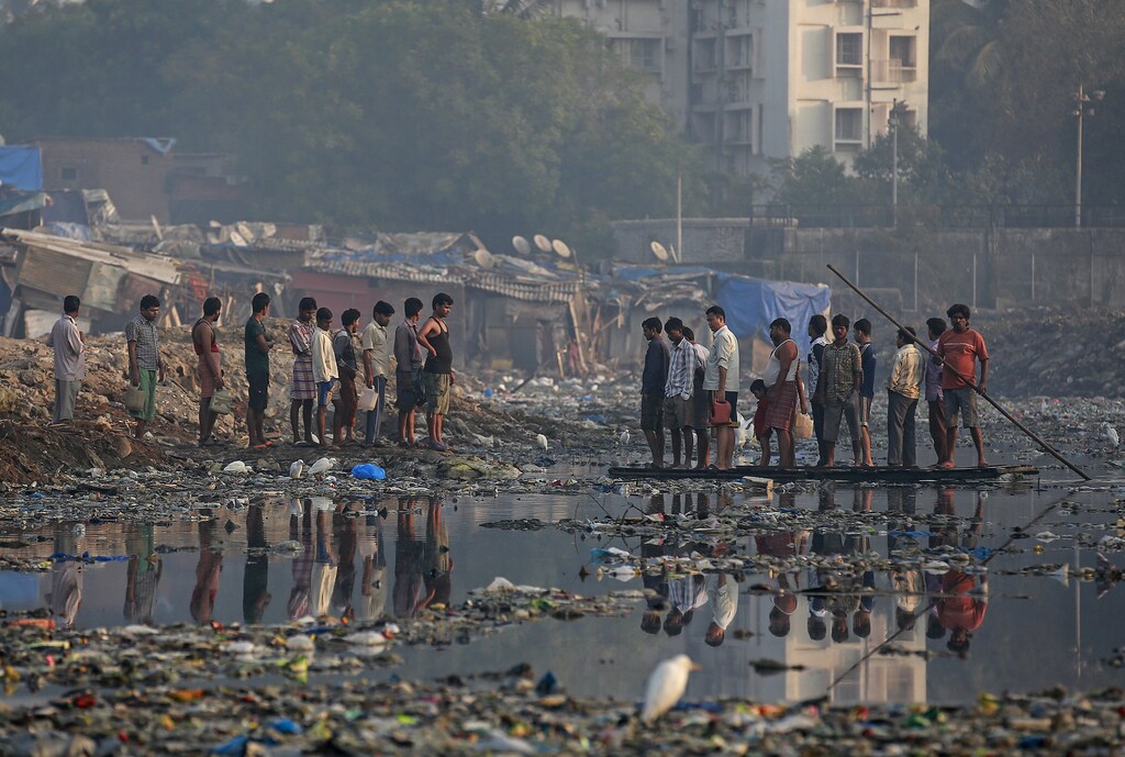 Residents use an improvised raft to cross a sewage canal at a slum in Mumbai February 11, 2015. Residents pay 2 Indian rupees ($0.03) for a single trip. REUTERS/Danish Siddiqui (INDIA - Tags: SOCIETY ENVIRONMENT) - GM1EB2B19BG01