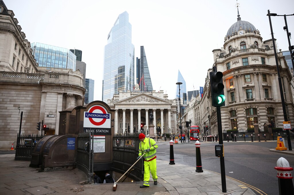 A worker sweeps a pavement at an empty Bank Junction, amid the coronavirus disease outbreak, in London, Britain.