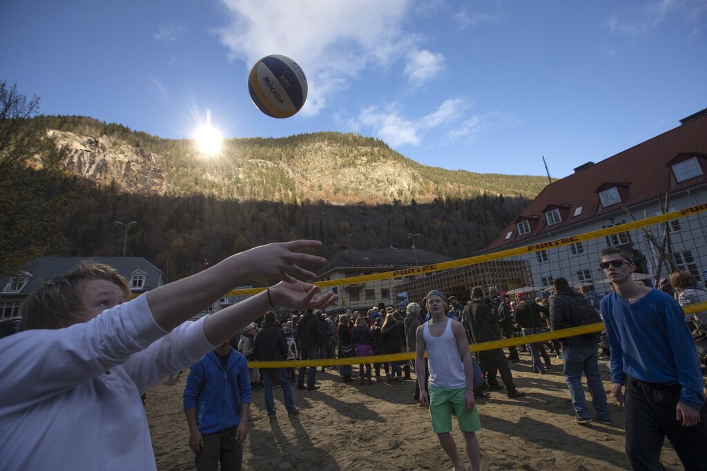 People play volleyball during the official opening of giant sun mirrors (top) erected on the mountainside, in the town of Rjukan October 30, 2013. The town, surrounded by mountains high enough to deprive its inhabitants of direct sunlight during winter, would be able to receive sunlight in the central square from deflected sunrays from the mirrors. REUTERS/Terje Bendiksby/NTB Scanpix (NORWAY - Tags: SOCIETY ENVIRONMENT) ATTENTION EDITORS - THIS IMAGE WAS PROVIDED BY A THIRD PARTY. THIS PICTURE IS DISTRIBUTED EXACTLY AS RECEIVED BY REUTERS, AS A SERVICE TO CLIENTS. NORWAY OUT. NO COMMERCIAL OR EDITORIAL SALES IN NORWAY. NO COMMERCIAL SALES - GM1E9AU1PYZ01