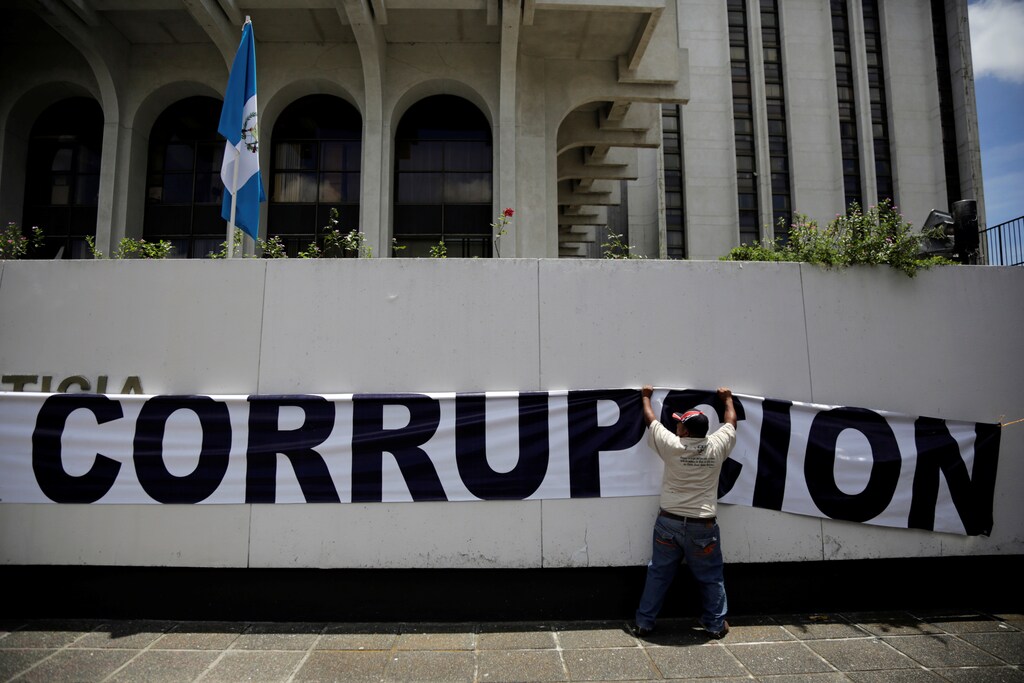 A man holds a banner reading "Corruption" outside Guatemala's Constitutional Court in Guatemala City, Guatemala September 4, 2017. REUTERS/Luis Echeverria - RC1F03472800