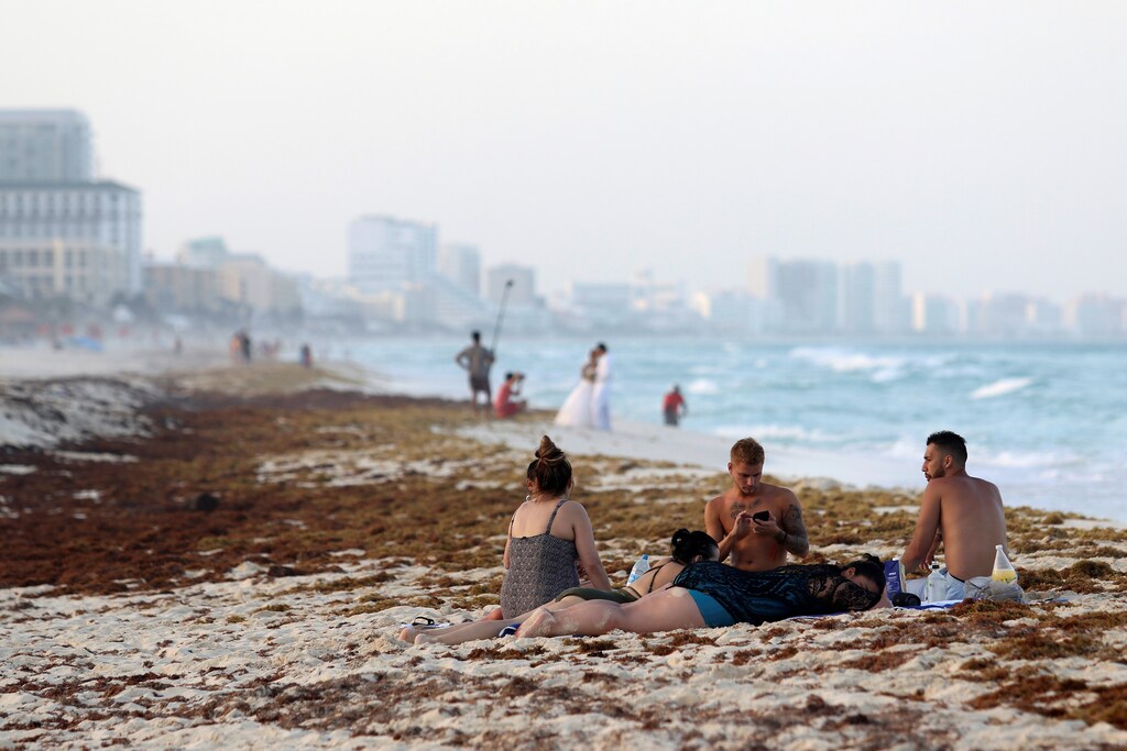 Tourists are seen on a beach covered wth seaweed in Cancun, Mexico June 24, 2019. REUTERS/Jorge Delgado - RC1913BE9290