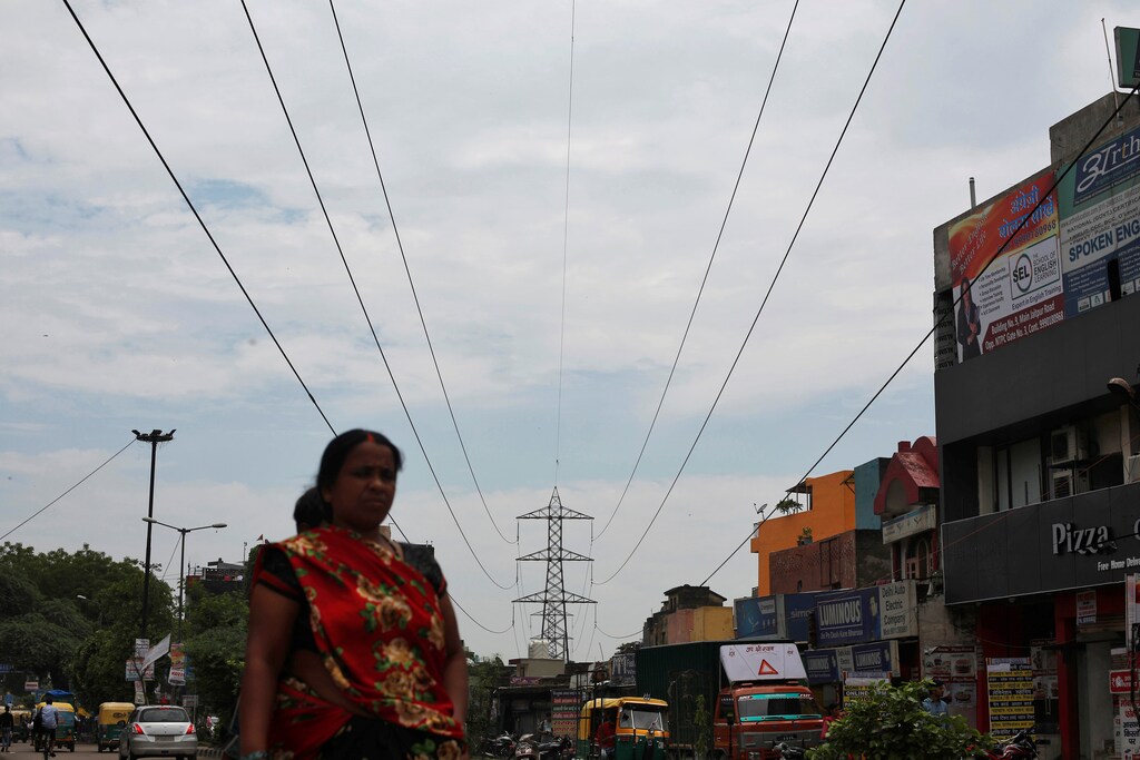 A woman walks under high-tension power lines near a coal-fired power plant in New Delhi, India, July 20, 2017. Picture taken July 20, 2017. REUTERS/Adnan Abidi - RC1A50A31DC0