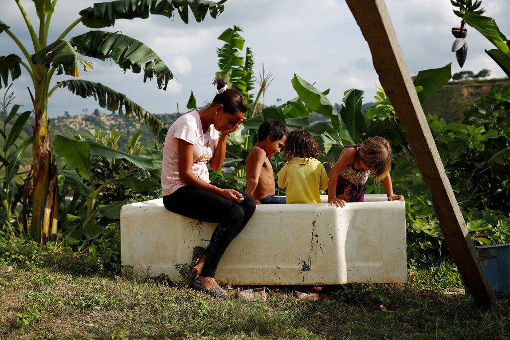 Lisibeht Martinez (L), 30, who was sterilized one year ago, sits next to her children while they play in a bathtub in the backyard of their house in Los Teques, Venezuela July 19, 2016. REUTERS/Carlos Garcia Rawlins SEARCH "STERILIZATION CHILD" FOR THIS STORY. SEARCH "THE WIDER IMAGE" FOR ALL STORIES. TPX IMAGES OF THE DAY - RTSKV3Q