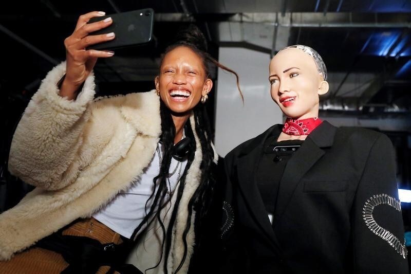 Model Adesuwa Aighewi takes a selfie as she is interviewed by Sophia, a humanoid robot created by Hanson Robotics, backstage before the "Alexander Wang Collection 2" presentation in Brooklyn, New York City, U.S., December 1, 2018. REUTERS/Andrew Kelly - RC1F55B1FDC0
