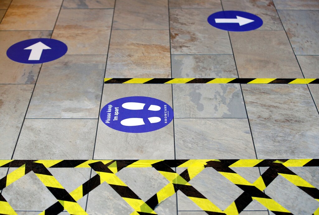 A social distancing sign and markers are pictured on the floor