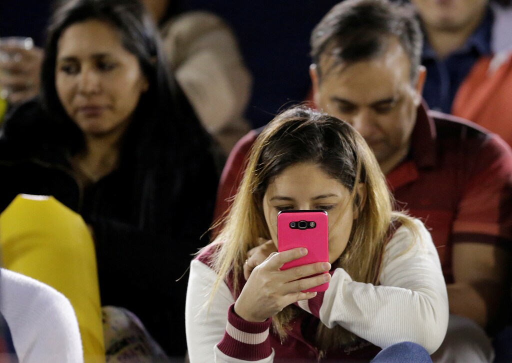 A football fan looks at a mobile phone before a match at the Defensores del Chaco stadium in Asuncion, Paraguay July 4, 2017. Picture taken July 4, 2017. REUTERS/Jorge Adorno - RC1826ACAAB0