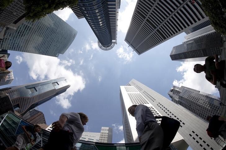 People walk past office buildings at the central business district in Singapore April 14, 2015. Singapore's central bank on Tuesday surprised markets by holding them off from further monetary easing, saying an improved outlook for global growth would underpin the trade-reliant economy. REUTERS/Edgar Su TPX IMAGES OF THE DAY