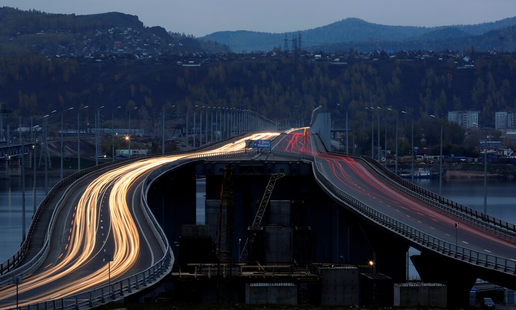 Vehicles drive along a bridge under construction across the Yenisei river in Krasnoyarsk, Russia, October 4, 2016. Picture taken with long exposure. REUTERS/Ilya Naymushin - RTSQPV3