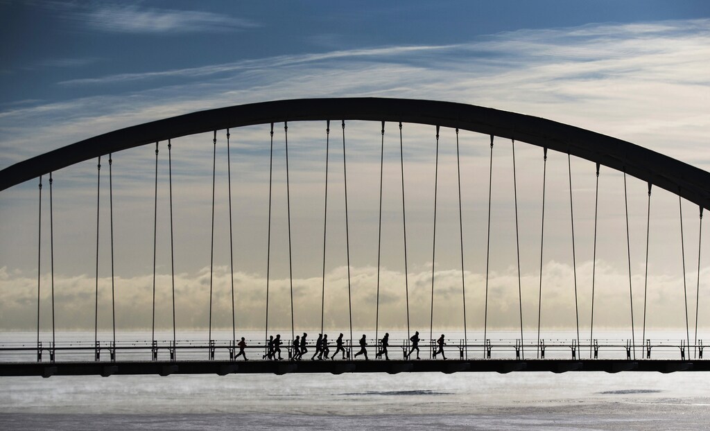 A group of joggers run across the Humber Bay Arch Bridge during extreme cold temperatures in Toronto, February 16, 2015. Toronto experienced some of the coldest weather of the year reaching -25C (-13F) on Sunday, as Environment Canada lifted its "extreme cold weather alert" Monday when temperatures warmed to -13C (8.6F), according to local reports. REUTERS/Mark Blinch (CANADA - Tags: ENVIRONMENT TPX IMAGES OF THE DAY) - GM1EB2H060R01
