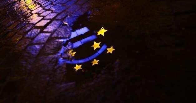 The Euro sculpture is partially reflected in a puddle on a cobblestone pavement in front of the headquarters of the European Central Bank (ECB) in Frankfurt January 21, 2012.
