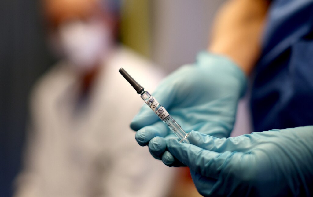 A healthcare worker of the free influenza vaccination programme holds a flu vaccine inside a tram, as the global spread of the the coronavirus disease (COVID-19) continues, in Vienna, Austria, October 1, 2020. REUTERS/Lisi Niesner - RC2L9J9A2QKE