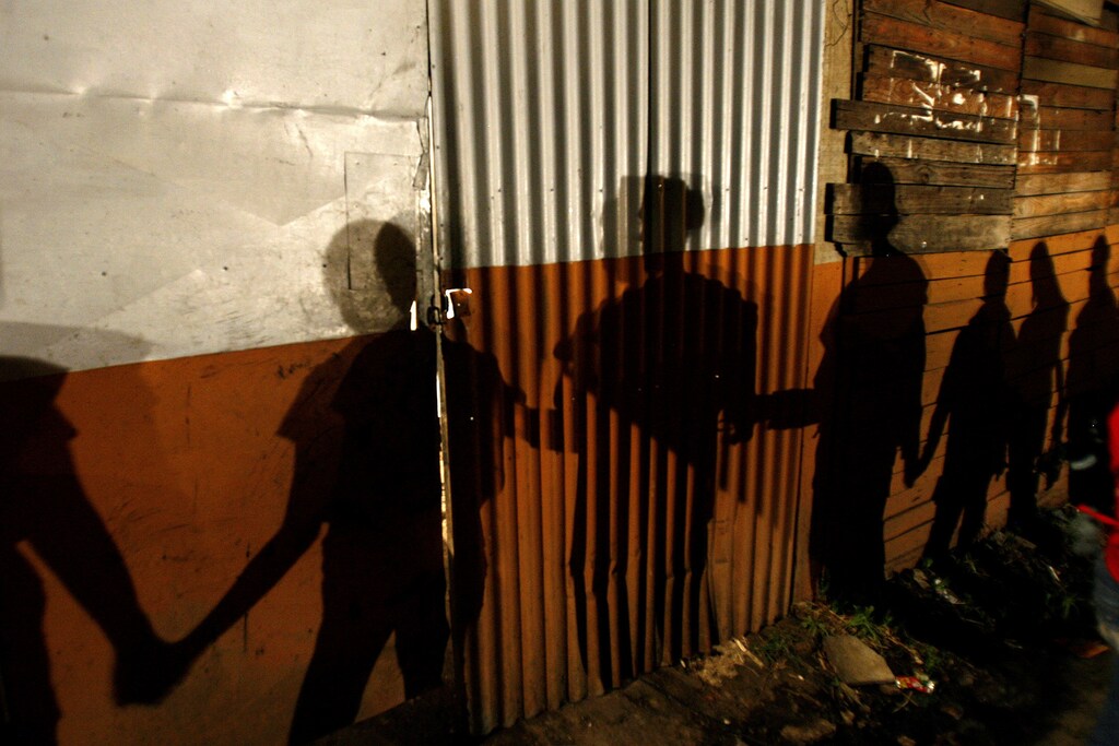 Shadows on a slum wall are cast by Nicaraguan immigrants to Costa Rica during a prayer session in the poor neighborhood of Triangulo de la Solidaridad north of San Jose, September 13, 2007. More than 3000 Nicaraguans live in conditions of poverty in this neighborhood. REUTERS/Juan Carlos Ulate (COSTA RICA) - GM1DWDNFMWAA