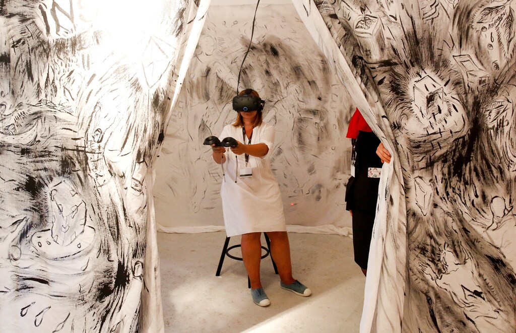 A woman tries on earphones and a headset used for virtual reality at the Venice Virtual Reality a competition during 74th Venice Film Festival in Venice, Italy, August 29, 2017.