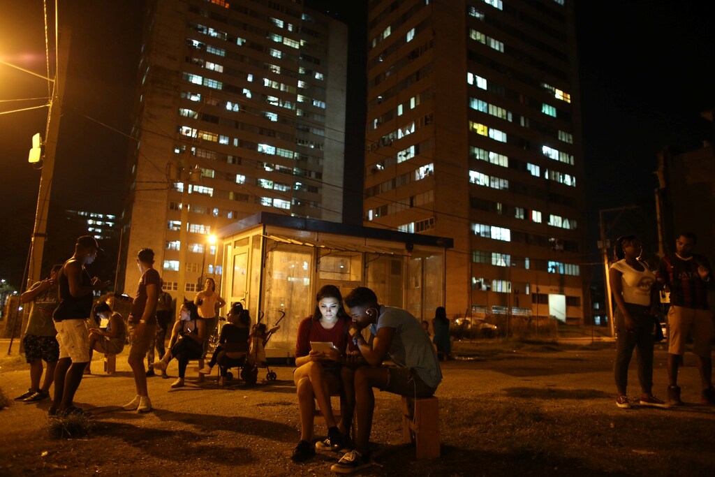 Carolina Gutierrez (center L), 17, and Neuil Valdez, 18, use mobile phones to connect to the internet at a hotspot in downtown Havana, Cuba, December 12, 2016. REUTERS/Alexandre Meneghini - RTX2UQOG