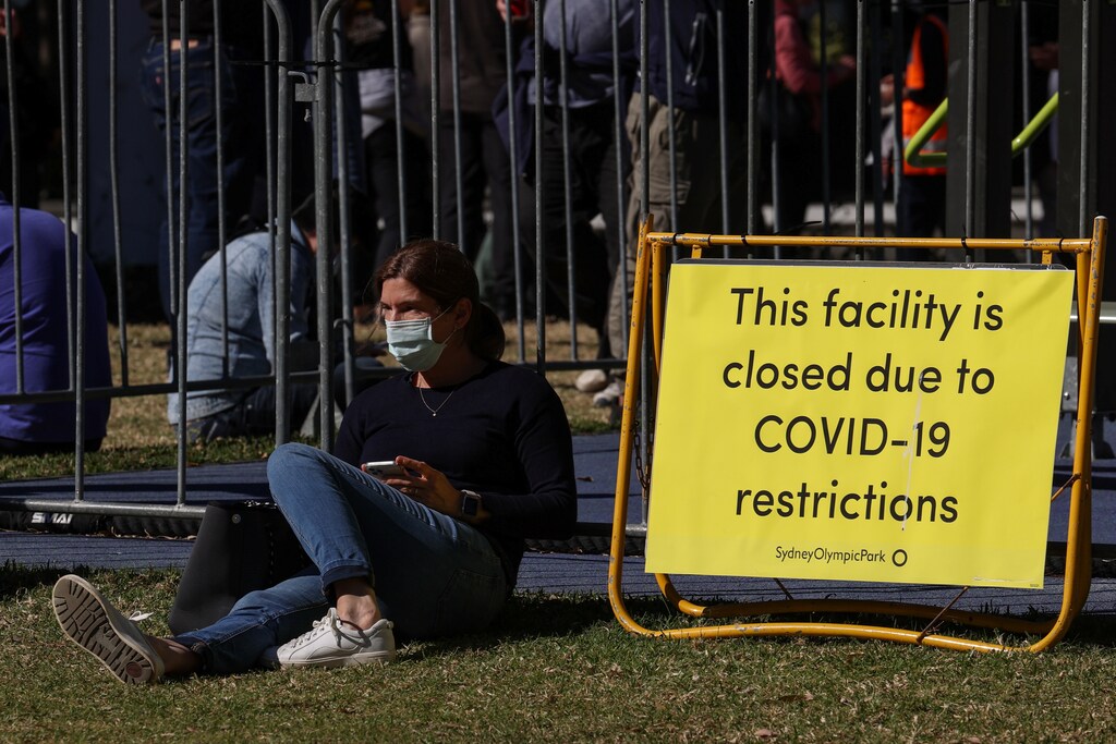 People spread out in a park while waiting for their appointments outside a coronavirus disease (COVID-19) vaccination centre at Sydney Olympic Park during a lockdown to curb the spread of an outbreak in Sydney, Australia, August 16, 2021. REUTERS/Loren Elliott - RC226P9Z4ECE