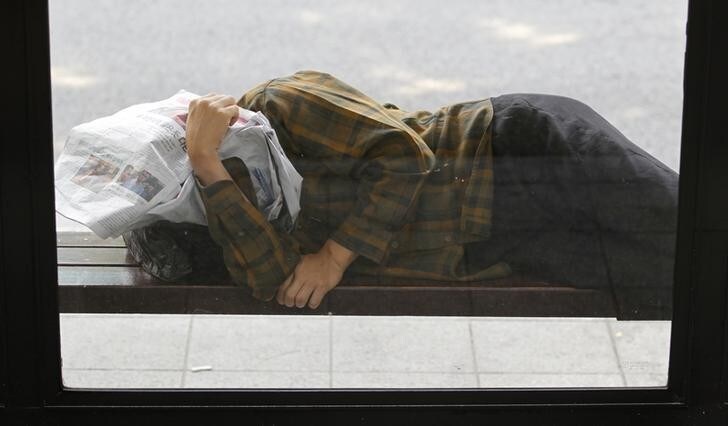 A homeless man takes a nap at a bus stop in central Seoul June 19, 2012. Asian shares edged down on Tuesday as rising Spanish bond yields stoked fears its tottering banking system is dragging Madrid deeper into crisis, snuffing out a relief rally that followed a win for mainstream parties in Greece's weekend election. REUTERS/Lee Jae-Won (SOUTH KOREA - Tags: BUSINESS EMPLOYMENT)