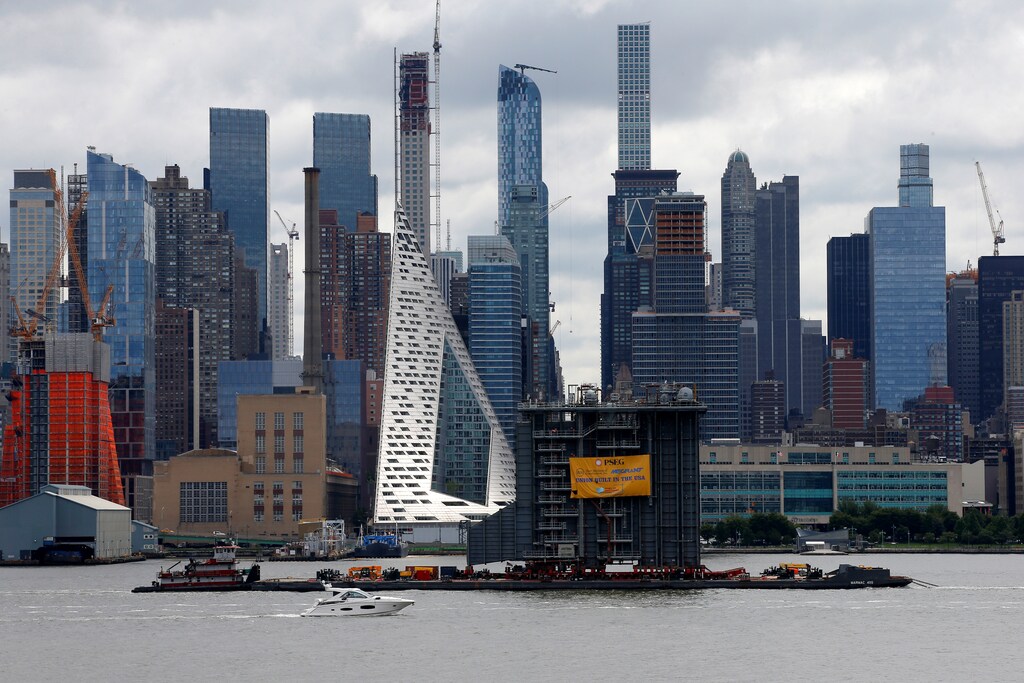 Tugboats transport a 4,000 ton, 125 foot tall heating structure constructed for a new power plant on a 400 foot-long barge south on the Hudson River past New York City, U.S., as it passes midtown Manhattan as seen from Weehawken, New Jersey, U.S., August 8, 2017. REUTERS/Mike Segar - RTS1AWT0