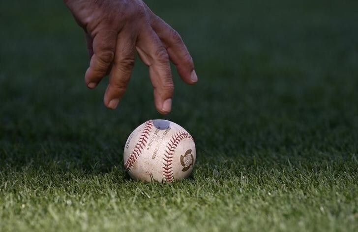 An umpire picks up a baseball during the World Baseball Classic Round 2 game between Japan and Cuba in San Diego, California March 15, 2009. REUTERS/Danny Moloshok (UNITED STATES SPORT BASEBALL)