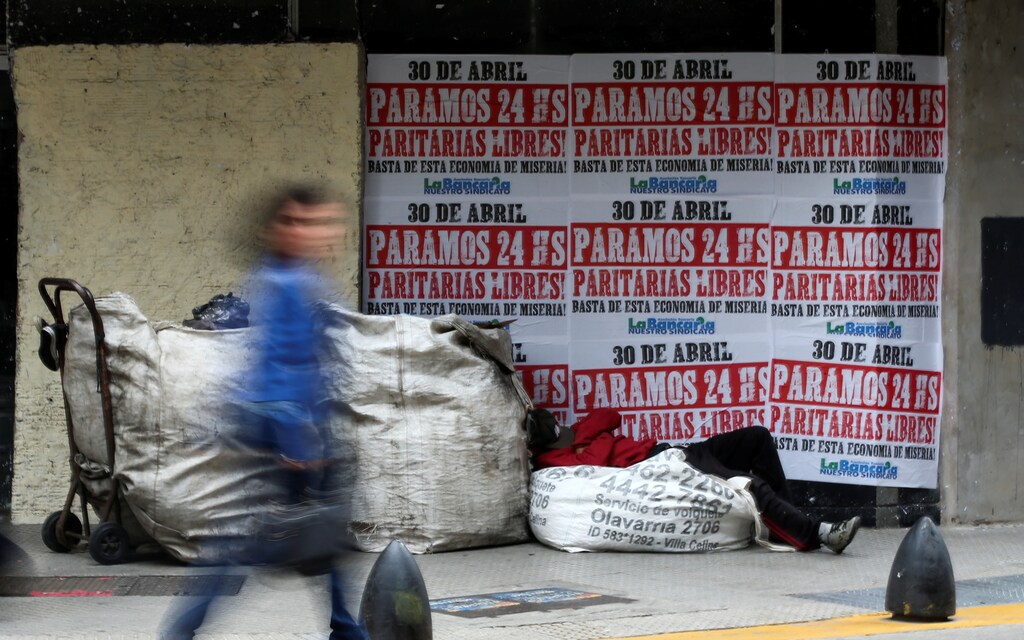 A homeless person sleeps outside a currency exchange shop with posters announcing a general strike action on April 30th in Buenos Aires' financial district, in Buenos Aires, Argentina April 25, 2019. REUTERS/Agustin Marcarian - RC13645914A0