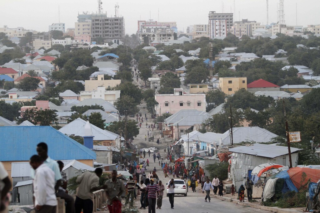 People walk along a street in Mogadishu September 28, 2013. Street lamps now brighten some of Mogadishu's battle-scarred roads and couples hold hands at the seaside next to bombed-out beachfront buildings, a scene that would have been unthinkable when the Islamist al Shabaab group held sway here. However, rebuilding a life many in the world take for granted is a slow process after more than 20 years of civil war and anarchy in Somalia. Islamists, who control swathes of countryside and some towns, have launched several attacks in Mogadishu, and last month they showed their reach, claiming responsibility for a deadly attack on a Kenyan shopping mall. Picture taken September 28, 2013. REUTERS/Feisal Omar (SOMALIA - Tags: CONFLICT POLITICS SOCIETY)ATTENTION EDITORS: PICTURE 01 OF 48 FOR PACKAGE 'DAILY LIFE IN MOGADISHU' SEARCH 'MOGADISHU BEACHFRONT' FOR ALL IMAGES - GM1E9AH1BV001