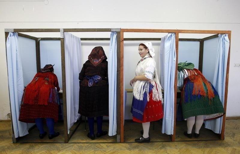 Hungarian women wearing traditional costumes fill in their ballot papers at a polling station during the European Parliamentary elections in Veresegyhaza, 30 km (19 miles) east of Budapest, June 7, 2009. REUTERS/Laszlo Balogh (HUNGARY POLITICS ELECTIONS IMAGES OF THE DAY SOCIETY) - GM1E56714LW01