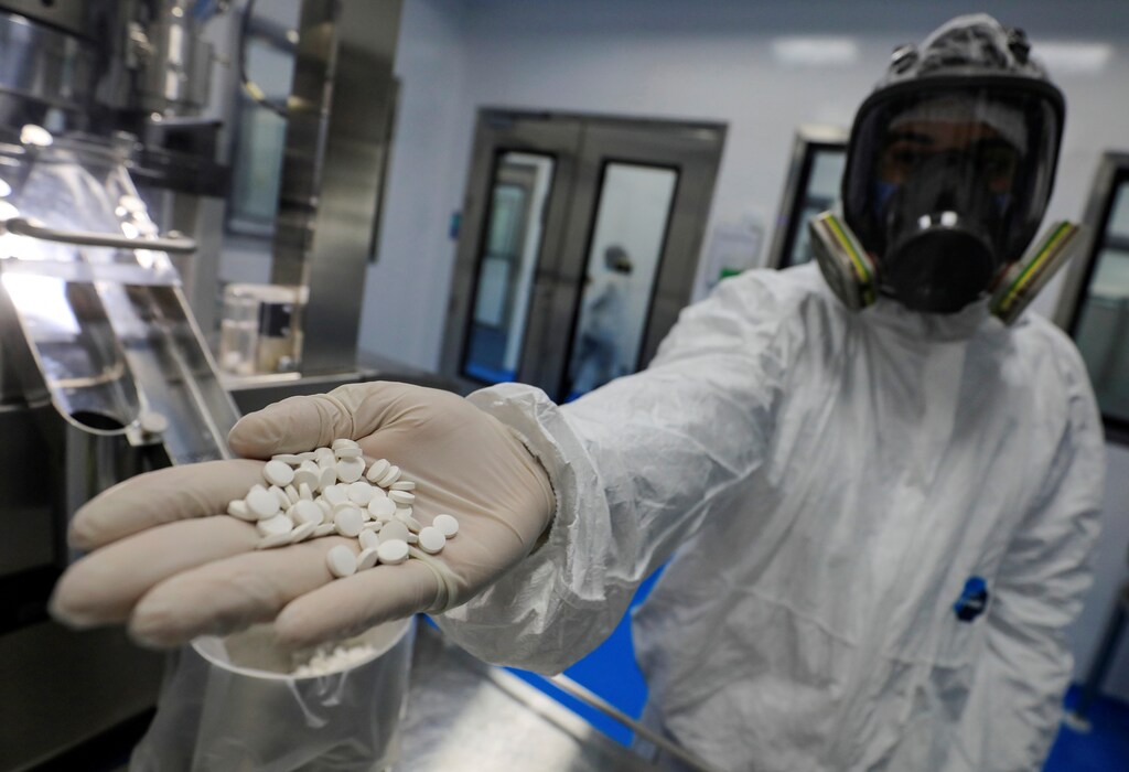 A lab technician wearing a full-face mask and a protective suit holds tablets of investigational coronavirus disease (COVID-19) treatment drug "Favipiravir" at Eva Pharma Facility in Cairo, Egypt June 25, 2020. Picture taken June 25, 2020. REUTERS/Amr Abdallah Dalsh - RC2XGH94FFJG