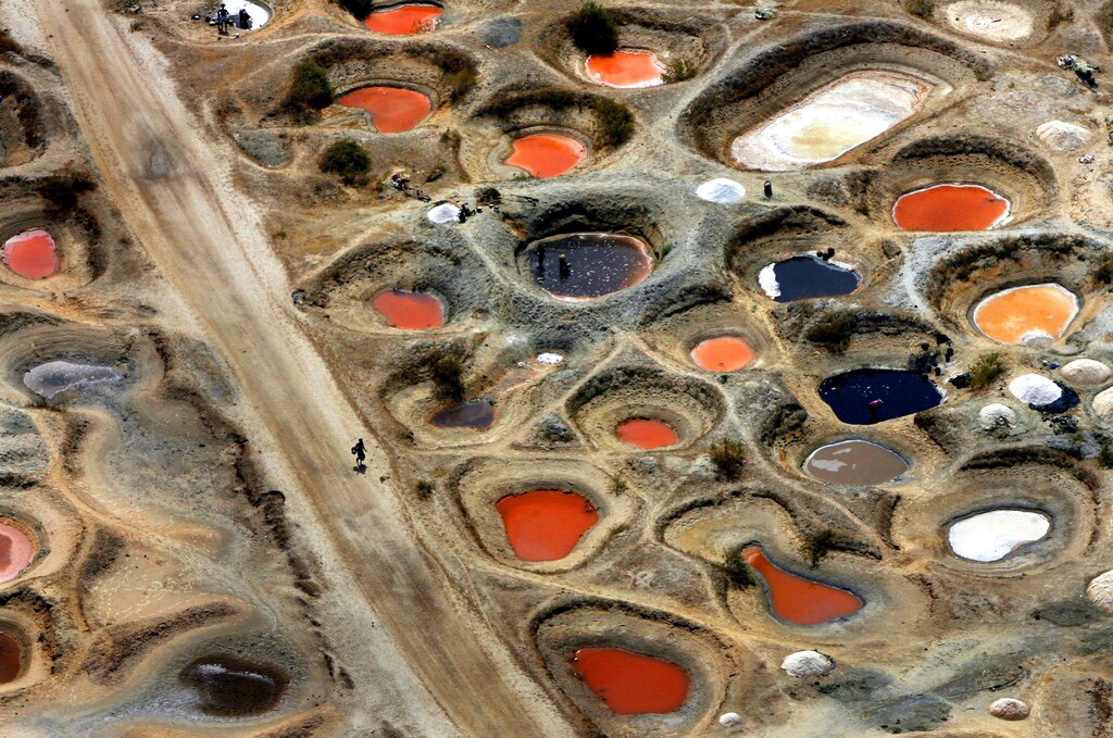 An aerial view shows pools of mineral-coloured water gathered on salt flats in holes dug by salt collectors on the Senegalese coastline near the border with Gambia June 12, 2006. Women collect salt by hand into 50kg (110lbs) sacks, which sell for about $2, and are traded with neighbouring Gambia and Mauritania, where salt is mainly used for preserving fish in areas without electricity. REUTERS/Finbarr O'Reilly (SENEGAL)FOR BEST QUALITY also see: GF1DSWQOEXAA - RTR1EDG8