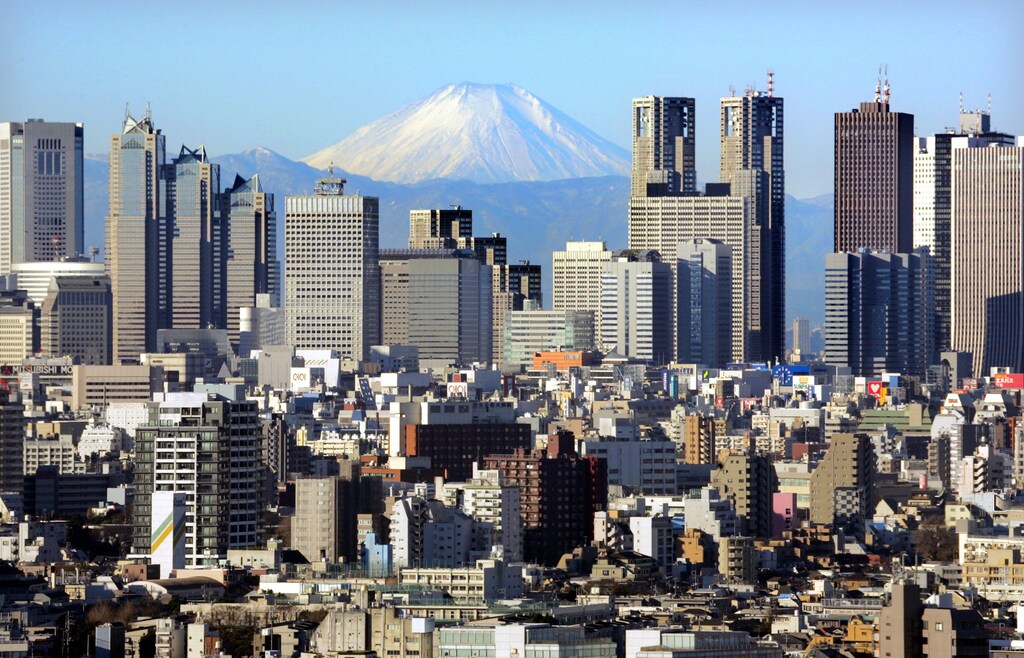 Japan's Mt Fuji, covered with snow, is seen through Shinjuku skyscrapers in Tokyo January 8, 2006. The recovery of Japan's economy has been helped by a strong recovery in exports and a rise in corporate profits that has filtered through to lower unemployment rates and raise incomes. The recovery has bolstered confidence in the stock market, where the Nikkei share average surged 40 percent in 2005. REUTERS/Kimimasa Mayama - RP3DSFDBQPAC