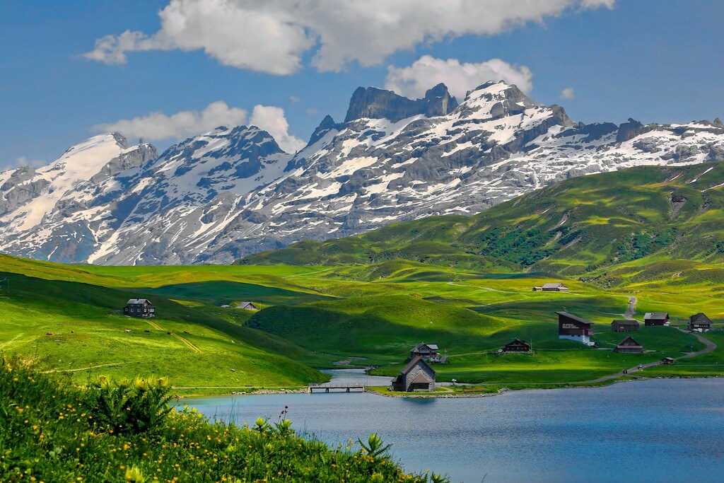 A view of the Swiss Alps, partly covered in snow, partly with grass.