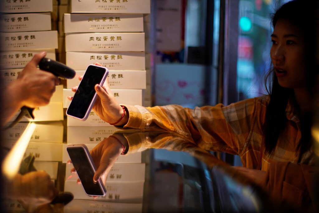 A woman gets her phone's QR code of the digital payment services scanned at a food shop, following the coronavirus disease (COVID-19) outbreak, in Shanghai, China October 10, 2020. REUTERS/Aly Song - RC2MFJ9WRM74