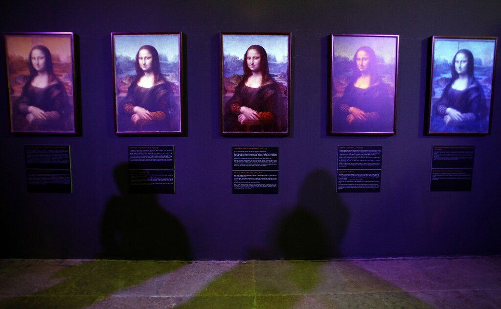 Visitors cast shadows on photographs, by French engineer Pascal Cotte, of the back of the Mona Lisa in the exhibition "Da Vinci - the genius" in the Museum of Artillery in St. Petersburg October 5, 2011. Cotte was allowed exclusive access to photograph the Mona Lisa with a specially developed digital camera that captured the look of the famous painting during various stages of its life. REUTERS/Alexander Demianchuk (RUSSIA - Tags: SOCIETY) - GM1E7A600C001