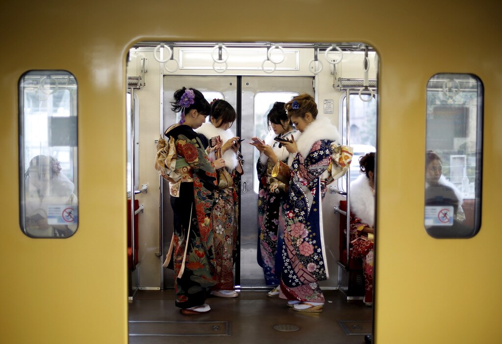 Japanese women wearing kimonos look at their mobile phones after their Coming of Age Day celebration ceremony at an amusement park in Tokyo January 11, 2016. According to a government announcement, more than 1.2 million men and women who were born in 1995 marked the coming of age this year, a decrease of approximately 50,000 from last year. REUTERS/Yuya Shino - GF20000091007