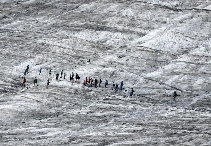 Tourists walk along a glacier during a simulated Mars mission on Tyrolean glaciers in Kaunertal, Austria, August 7, 2015. The Austrian Space Forum is sending some of its researchers to practice weight-less walking in spacesuits on a glacier which resembles the terrain on Mars. REUTERS/Dominic Ebenbichler
