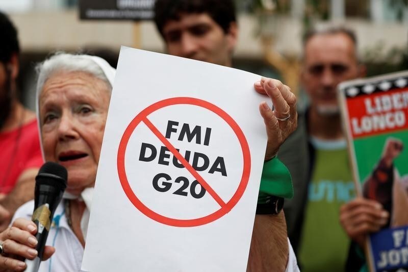 A woman, member of the human rights organisation Mothers of the Plaza de Mayo (Madres de la Plaza de Mayo), holds a banner reading "IMF, Debt G20" during a protest, ahead of the Group 20 summit, in Buenos Aires, Argentina November 29, 2018. REUTERS/Carlos Garcia Rawlins - RC1A9406E620
