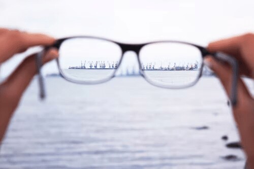 Person holding eyeglasses. The prevalence of short-sightedness in children has been rising, the WHO warns.