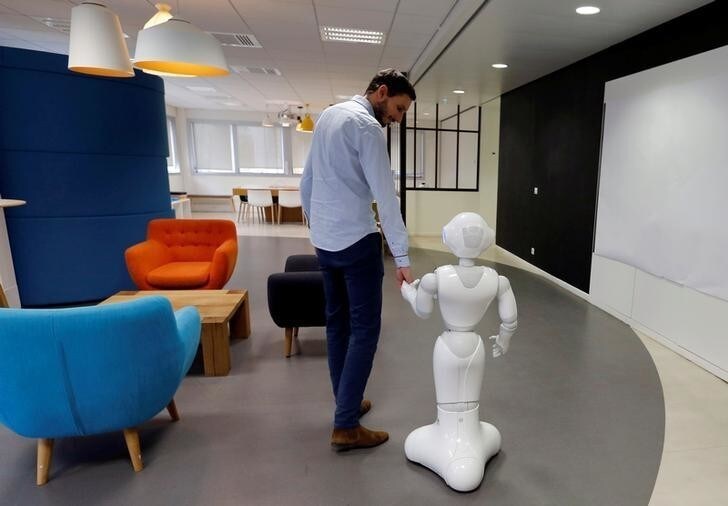 An employee of SoftBank Robotics walks with the Robot Assistant Pepper in Paris, France, March 9, 2018. Picture taken March 9, 2018. REUTERS/Regis Duvignau