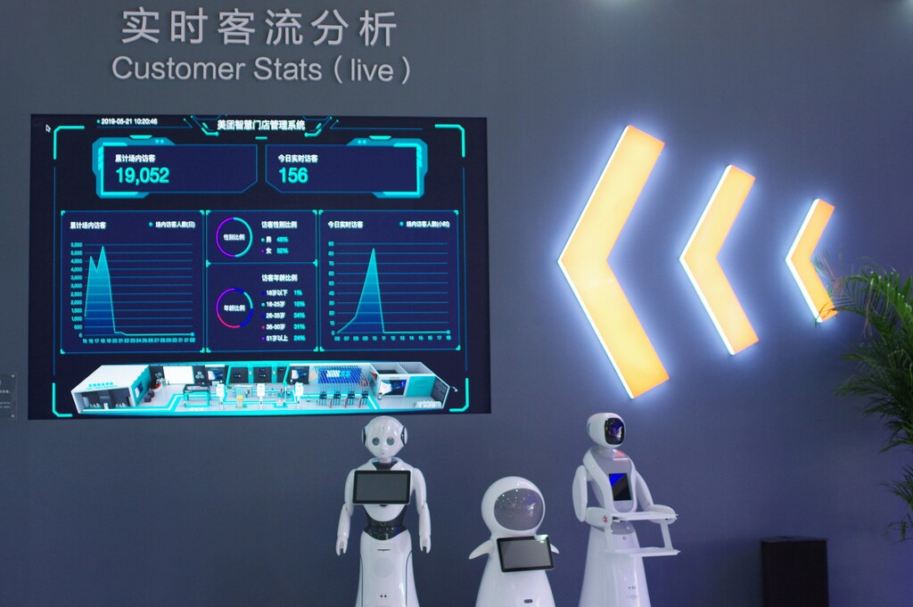 Robots are seen next to a screen showing Meituan's smart retailing management system at the Asian Cuisine Festival, held as a sideline event of the Conference on Dialogue of Asian Civilizations (CDAC), in Beijing, China May 21, 2019. Picture taken May 21, 2019. Qin Cansong/Qianlong.com via REUTERS ATTENTION EDITORS - THIS IMAGE WAS PROVIDED BY A THIRD PARTY. CHINA OUT. NO COMMERCIAL OR EDITORIAL SALES IN CHINA.