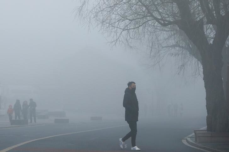 People walk on the road leading to the Badaling section of the Great Wall on a hazy day in Yanqing district in Beijing, China February 27, 2018. REUTERS/Thomas Peter
