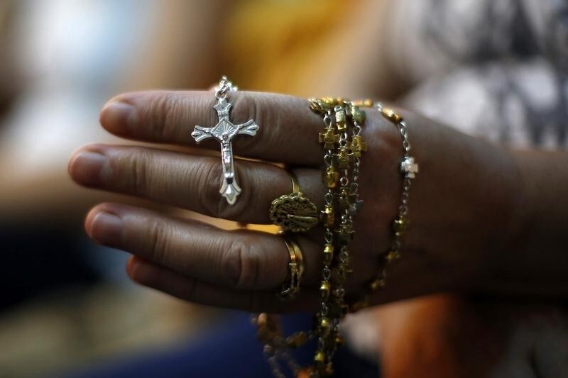 An Iraqi Christian woman holds a cross during a mass at the Church of the Virgin of Nasiriyah in Amman July 30, 2014. Hundreds of Christians in Jordan held a mass to pray for peace for Christians in Gaza, Iraq and Syria. REUTERS/Muhammad Hamed (JORDAN - Tags: POLITICS RELIGION CONFLICT CIVIL UNREST) - RTR40PL7
