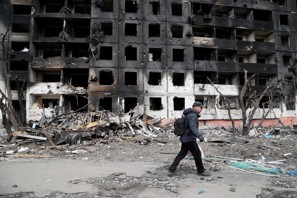 A man walks near a block of flats, which was destroyed during the Russian invasion of Ukraine in the besieged southern port city of Mariupol.
