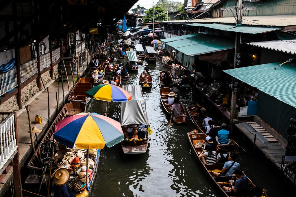 People riding in boats near marketplace in Bangkok, Thailand: Cities must start committing to nature-positive actions