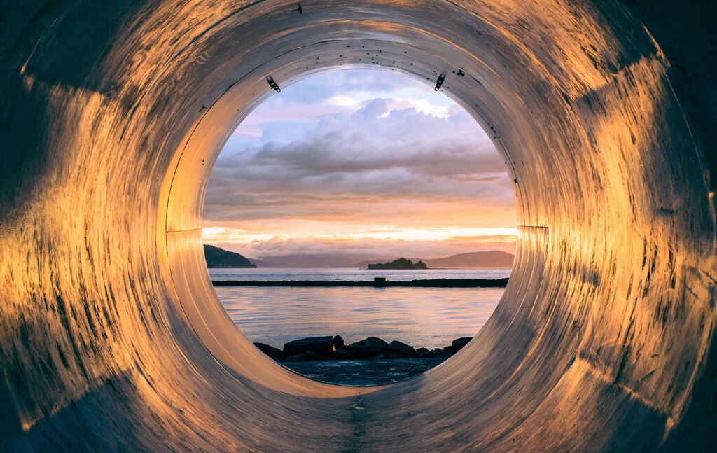 A seascape seen through the mouth of a pipe, illustrating the need to create a circular, ethical supply chain