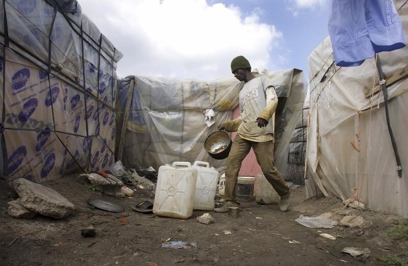 An African immigrant cooks in a makeshift camp in the countryside near the village of Rignano Garganico, southern Italy, September 23, 2009. Every year thousands of immigrants, many of them from Africa, flock to the fields and orchards of southern Italy to eke out a living as seasonal workers picking grapes, olives, tomatoes and oranges. Broadly tolerated by authorities because of their role in the economy, they endure long hours of backbreaking work for as little as 15-20 euros ($22-$29) a day and live in squalid makeshift camps without running water or electricity. Picture taken September 23, 2009. REUTERS/Tony Gentile