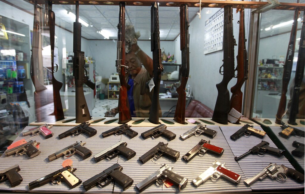 A shopkeeper wipes a glass display at a gun shop in Bangkok October 12, 2012. A tourist haven and regional base for multinational companies, Thailand has the highest number of guns in civilian hands in Southeast Asia -- almost four times more than the Philippines, a country notorious for violent gun crime. Picture taken October 12, 2012. To match Feature THAILAND-GUNS/ REUTERS/Sukree Sukplang (THAILAND - Tags: POLITICS SOCIETY) - GM1E8AM0IZL01