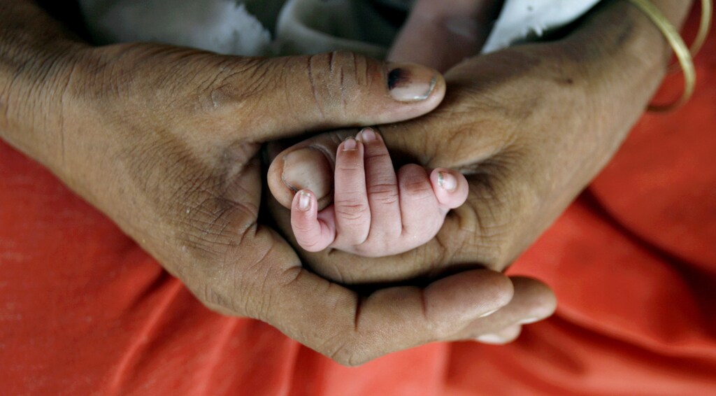 Bismillah holds the hand of her newly born child as she feeds her in Akhera village in the northern Indian state of Haryana July 4, 2007. Mohammad Ishaq, 50, a labourer, and his wife Bismillah, 40, have 23 children between the two of them, out of which 3 died and the last one was born in June this year, local media reported. Picture taken July 4, 2007. REUTERS/Adnan Abidi (INDIA) - GM1DVQCTZOAA
