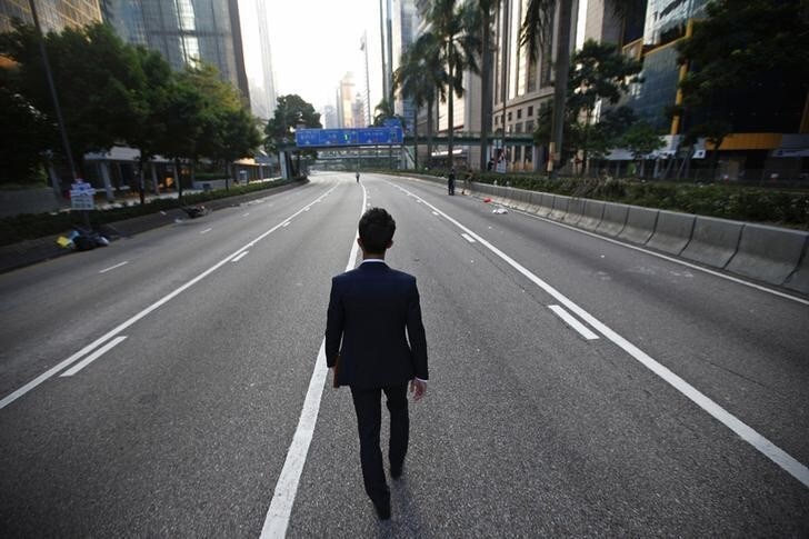 A man walks along an empty street near the central financial district in Hong Kong September 30, 2014. Tens of thousands of pro-democracy protesters extended a blockade of Hong Kong streets on Tuesday, stockpiling supplies and erecting makeshift barricades ahead of what some fear may be a push by police to clear the roads before Chinese National Day. REUTERS/Carlos Barria (CHINA - Tags: POLITICS CIVIL UNREST)
