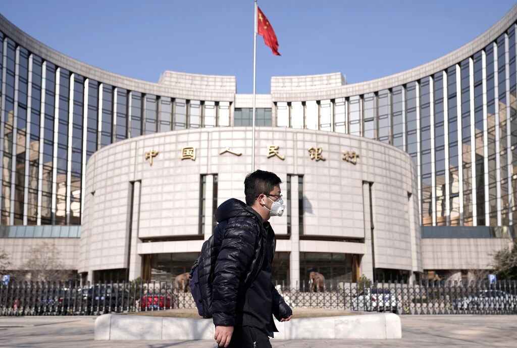 A man wearing a mask walks past the headquarters of the People's Bank of China, the central bank, in Beijing, China, as the country is hit by an outbreak of the new coronavirus, February 3, 2020
